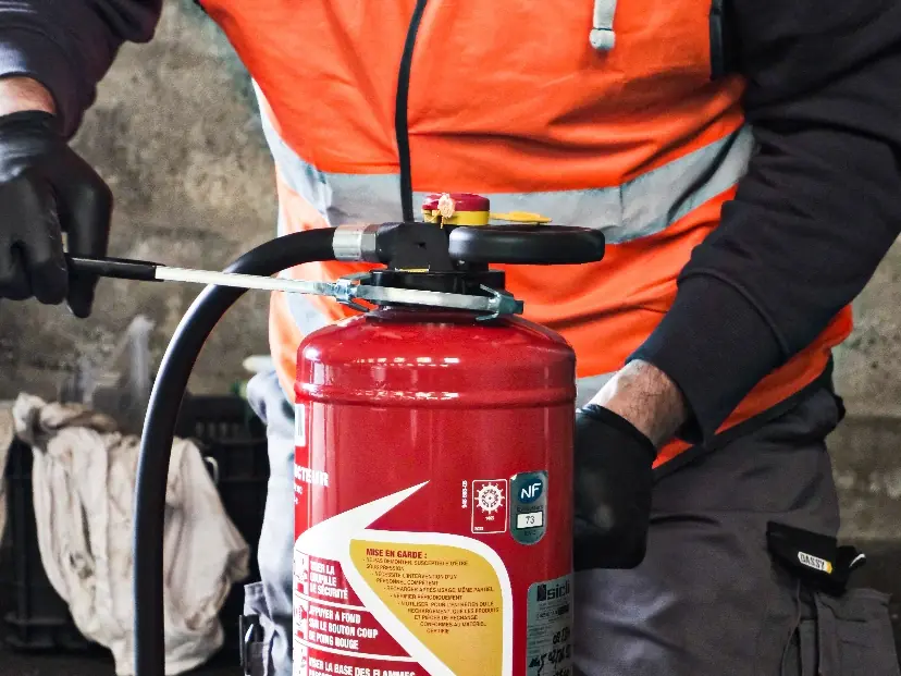 Technicien manipulant un extincteur lors d’une opération d’installation ou de contrôle