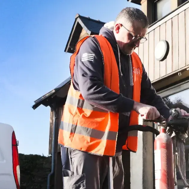 Professionnel installant un extincteur devant un établissement